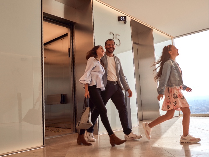 People smiling as they walk out of an elevator