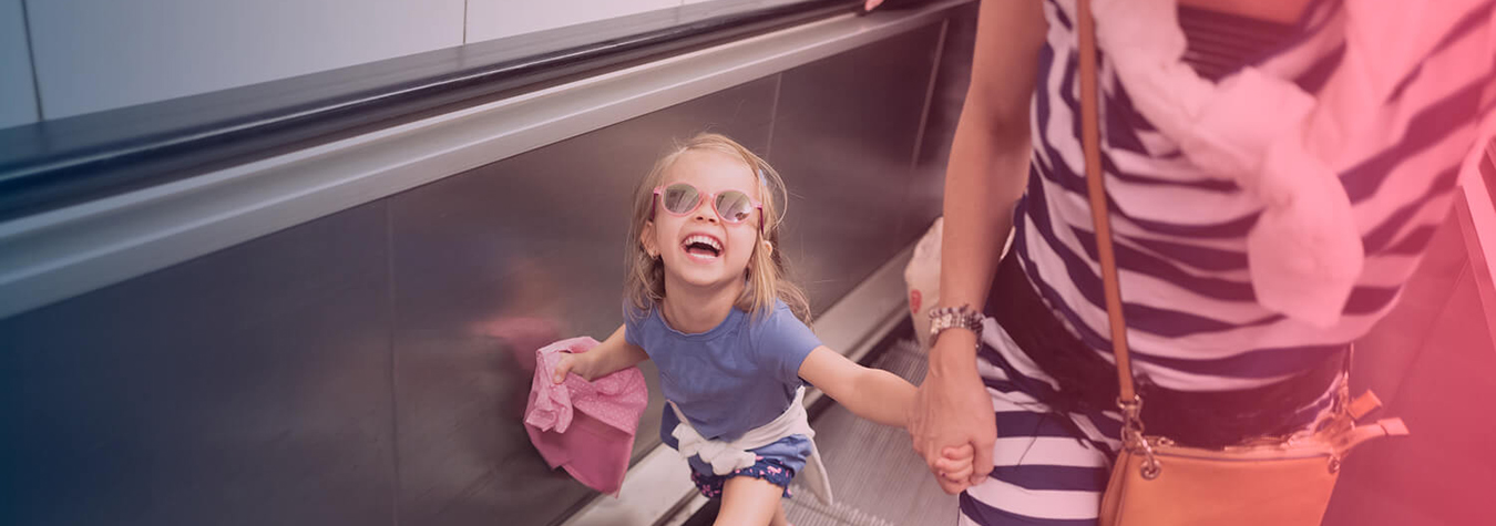 Woman holding hands with a child on an escalator