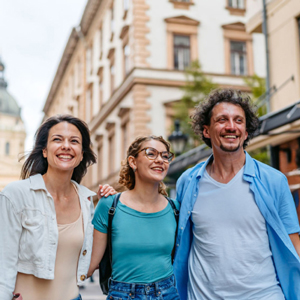 Three people smiling with buildings in the background
