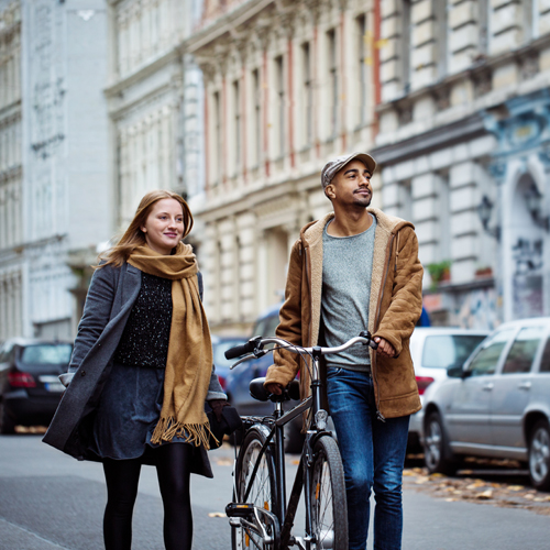 Man and woman walking down street with bicycle